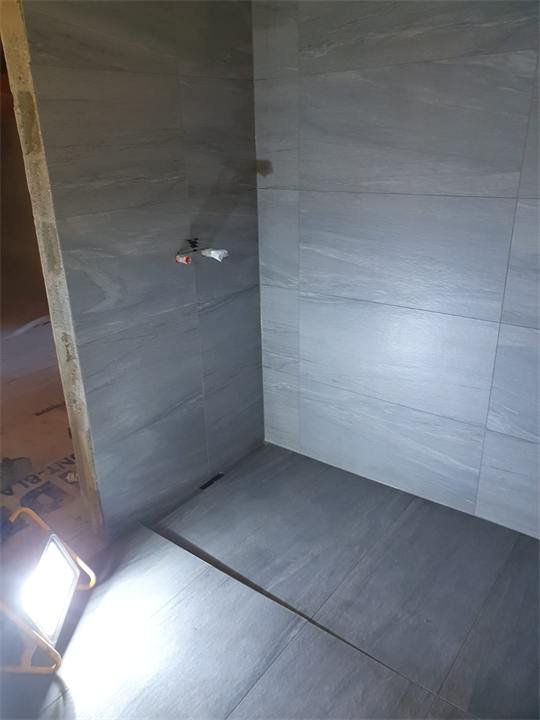 Pose de carrelage grand format dans une douche à l'italienne