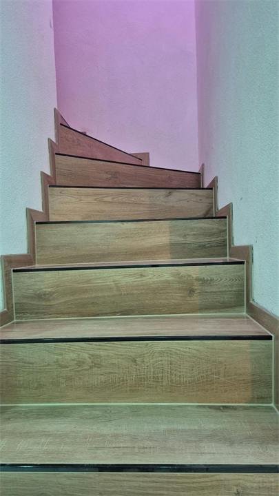 Escalier carrelé effet bois avec nez de marche noirs, vu depuis le bas
