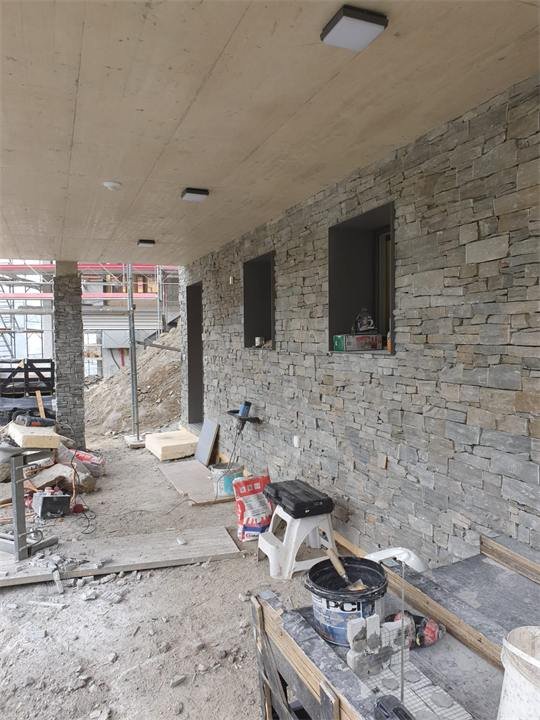 Mur en parement de pierre naturelle sous une terrasse couverte