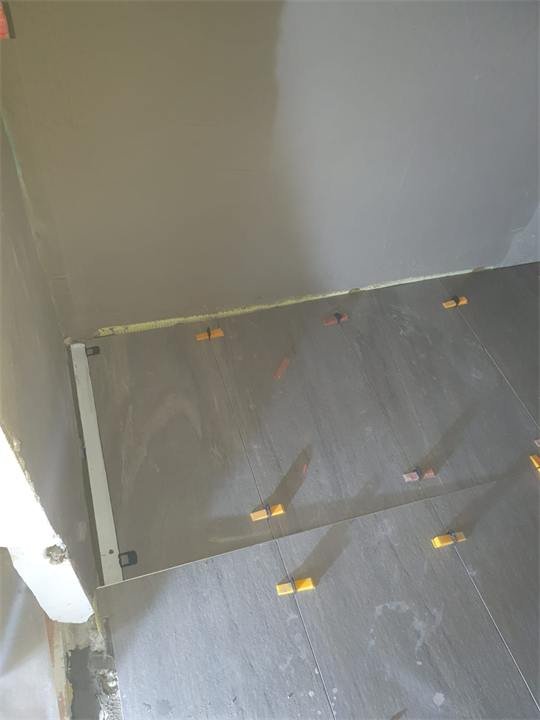 Carrelage gris en cours de pose, joints réguliers