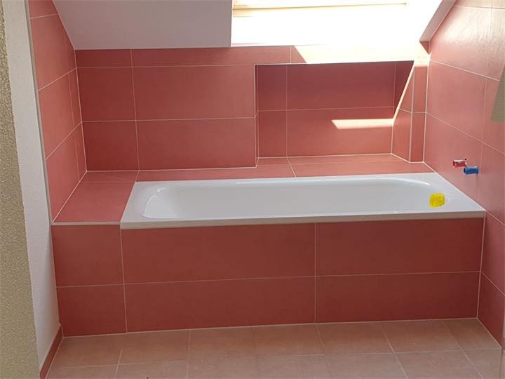 Salle de bain avec carrelage rouge et baignoire encastrée